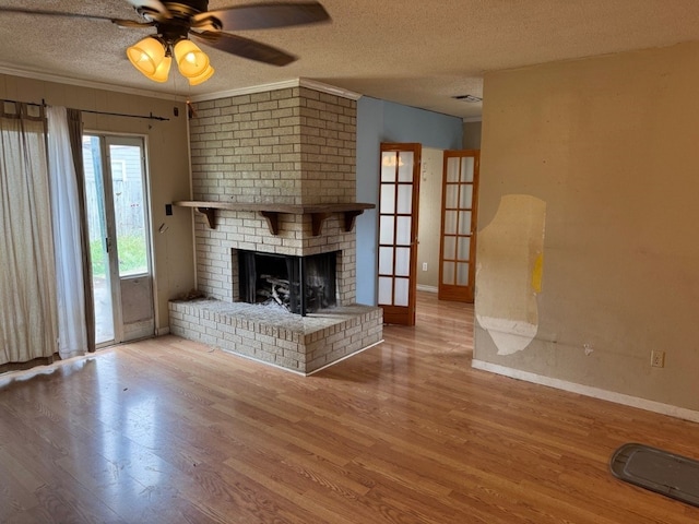 2100 Heights Blvd, Taylor, TX 76574 - unfurnished living room featuring wood finished floors, a textured ceiling, a fireplace, a ceiling fan, and ornamental molding