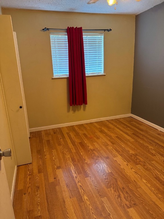 2100 Heights Blvd, Taylor, TX 76574 - spare room featuring wood finished floors and a textured ceiling