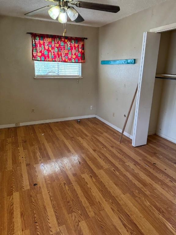 2100 Heights Blvd, Taylor, TX 76574 - unfurnished bedroom featuring wood finished floors, a ceiling fan, and a textured ceiling