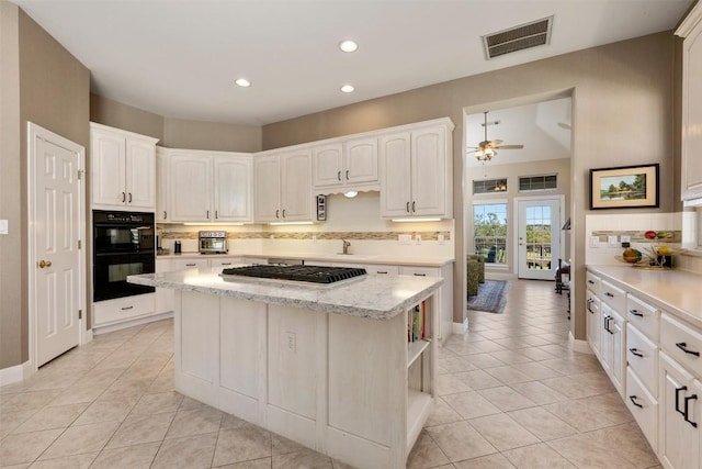 6 Radnor Dr, Austin, TX 78738 - kitchen with light tile patterned floors, ceiling fan, backsplash, stainless steel gas stovetop, and a center island
