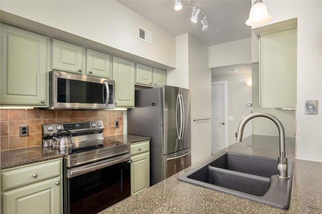 7701 Rialto Blvd Unit 617, Austin, TX 78735 - kitchen with stainless steel appliances, a sink, tasteful backsplash, green cabinets, and dark stone countertops