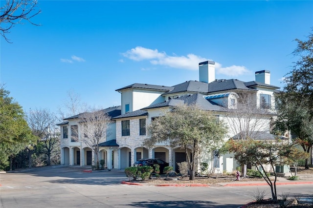 7701 Rialto Blvd Unit 617, Austin, TX 78735 - view of front of home with a chimney, stone siding, stucco siding, and concrete driveway