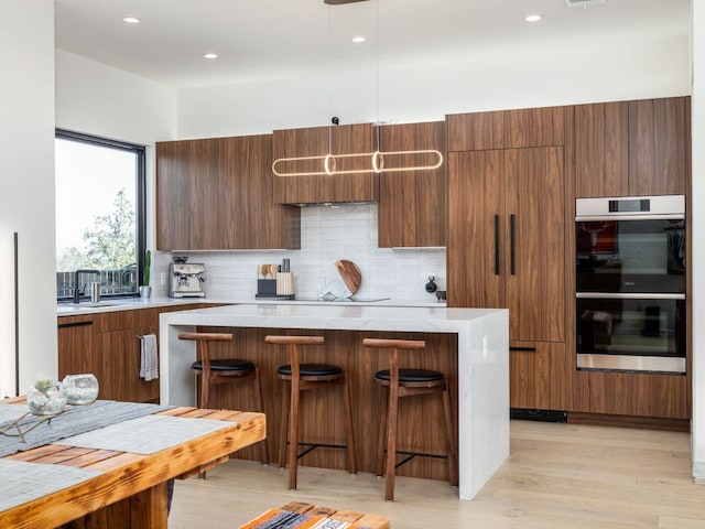 1510 Bellaire Dr, Austin, TX 78741 - kitchen featuring stainless steel double oven, modern cabinets, light wood finished floors, light countertops, and recessed lighting