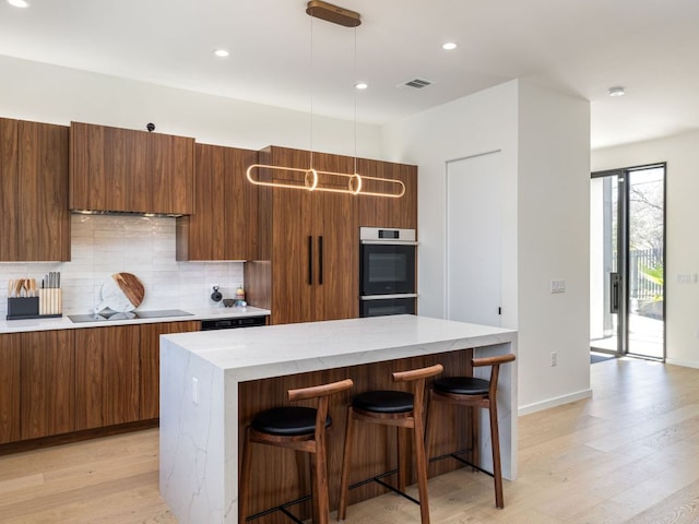 1510 Bellaire Dr, Austin, TX 78741 - kitchen featuring modern cabinets, light wood-type flooring, a center island, tasteful backsplash, and a breakfast bar