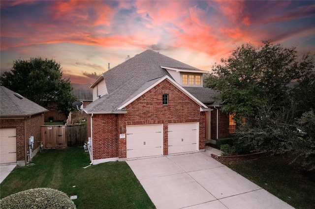 traditional-style house featuring concrete driveway, roof with shingles, brick siding, a garage, and a lawn