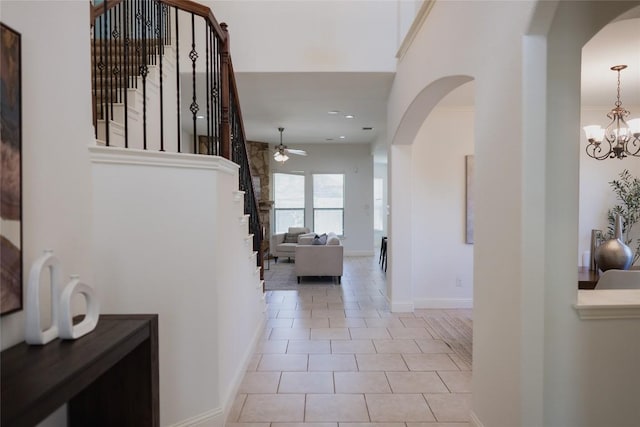 hall with tile patterned floors, baseboards, stairway, and an inviting chandelier