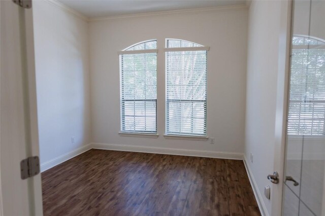 empty room with dark wood-type flooring, ornamental molding, baseboards, and a healthy amount of sunlight