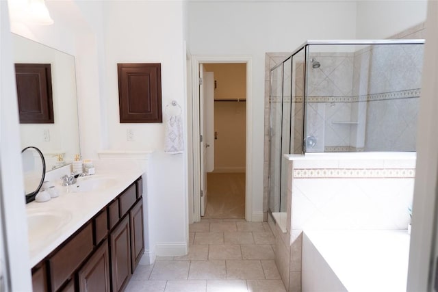 full bathroom with a bath, a shower stall, double vanity, a sink, and a walk in closet