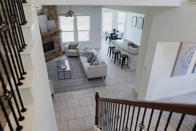 tiled living area featuring a sink, baseboards, a fireplace, and ceiling fan