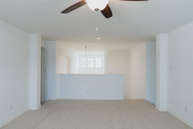carpeted spare room featuring baseboards, visible vents, and ceiling fan