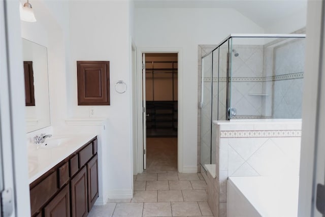 full bathroom with double vanity, a spacious closet, a sink, a stall shower, and tile patterned flooring