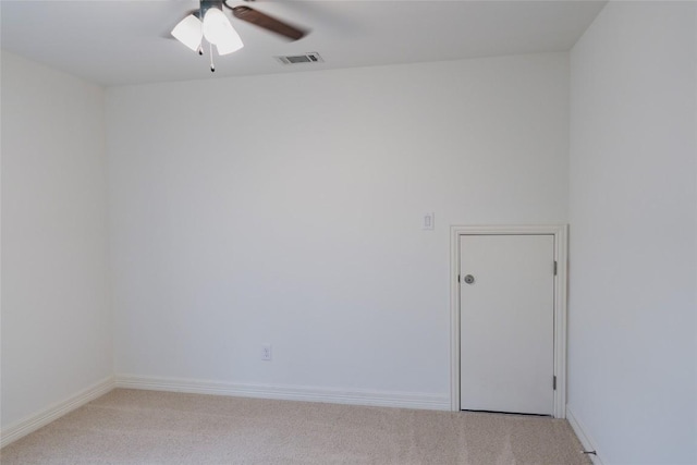 spare room with light colored carpet, visible vents, baseboards, and a ceiling fan