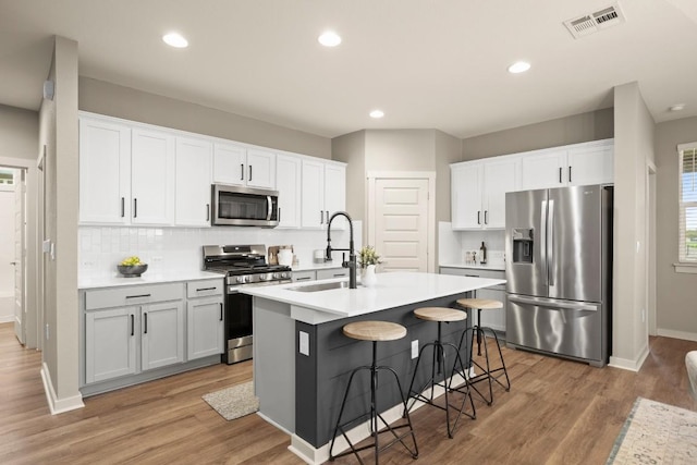 7800 Linnie Ln, Austin, TX 78724 - kitchen featuring appliances with stainless steel finishes, an island with sink, light wood-type flooring, light countertops, and a breakfast bar