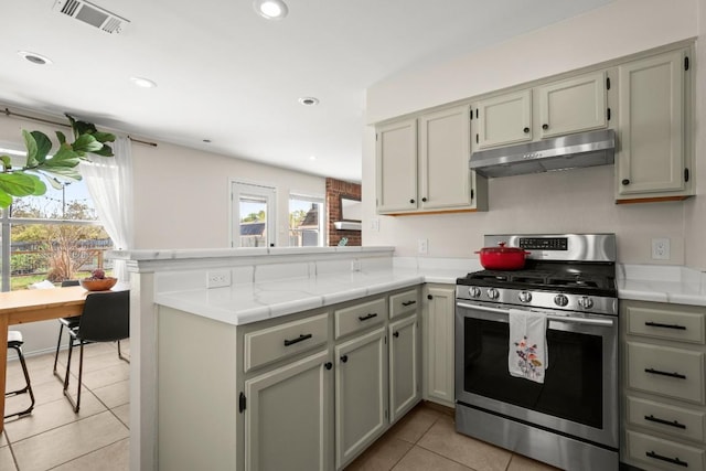 1302 Rambling Trl, Cedar Park, TX 78613 - kitchen with stainless steel range with gas cooktop, under cabinet range hood, a peninsula, light countertops, and light tile patterned floors