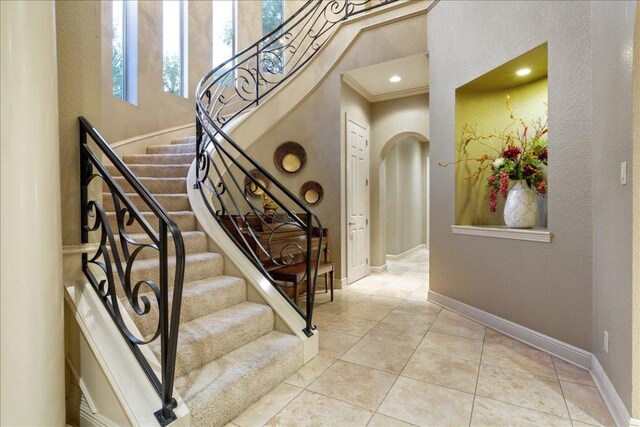 1317 Jack Nicklaus Cir, Salado, TX 76571 - staircase with baseboards, tile patterned floors, recessed lighting, arched walkways, and a high ceiling