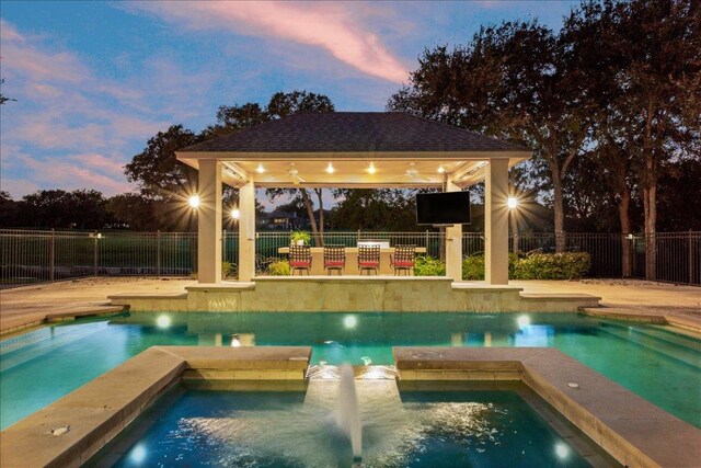 1317 Jack Nicklaus Cir, Salado, TX 76571 - pool at dusk featuring a gazebo, a pool with connected hot tub, fence, and a ceiling fan