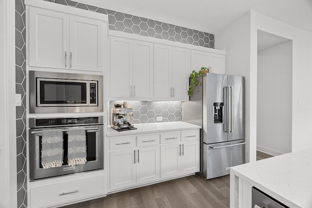 kitchen with decorative backsplash, appliances with stainless steel finishes, light countertops, dark wood-style flooring, and white cabinetry