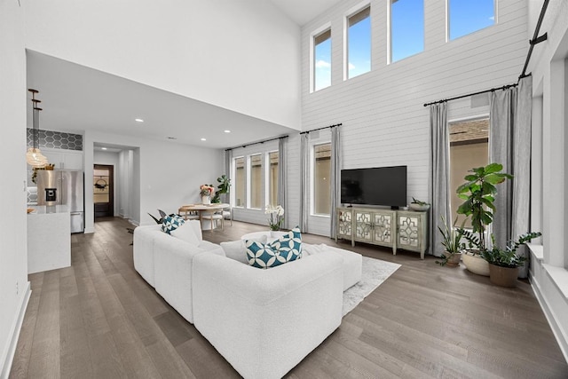 living area with a towering ceiling, recessed lighting, and wood finished floors