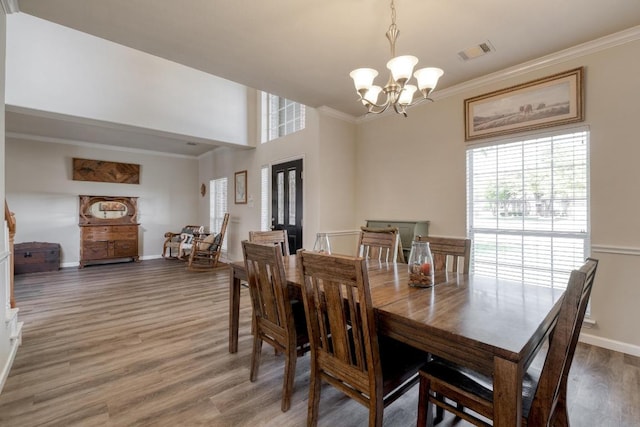 2209 Callaway Garden Ct, Pflugerville, TX 78660 - dining space featuring healthy amount of natural light, a chandelier, ornamental molding, light wood finished floors, and baseboards