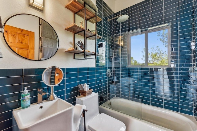 bathroom with tile walls, toilet, shower / bath combination, and a sink