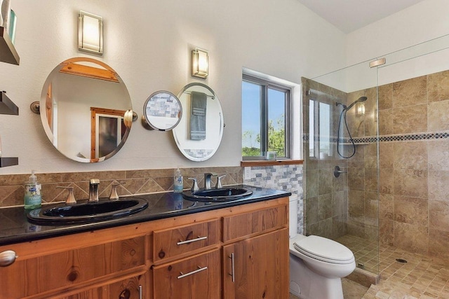 full bathroom featuring double vanity, a sink, toilet, and tiled shower