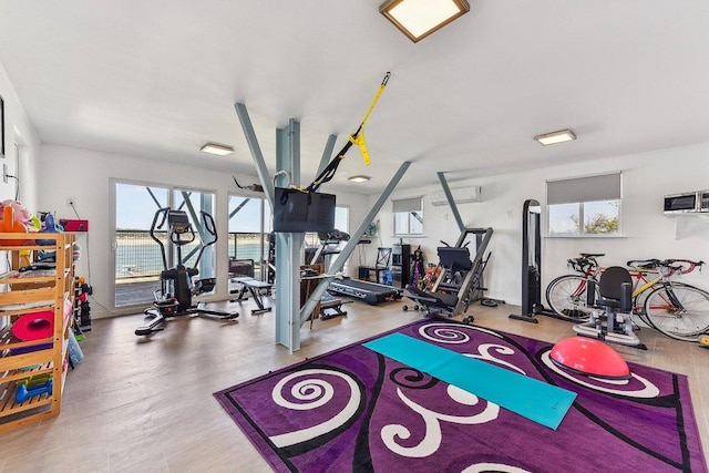 workout area with an AC wall unit and wood finished floors