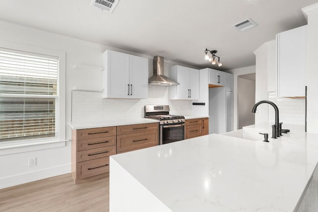 1290 Sweet Gum Dr, Kyle, TX 78640 - kitchen with wall chimney exhaust hood, stainless steel gas range, a sink, a peninsula, and tasteful backsplash