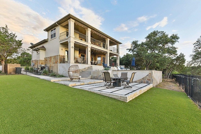 22000 Briarcliff Dr, Spicewood, TX 78669 - back of house with a fenced backyard, a balcony, a patio, stone siding, and stucco siding