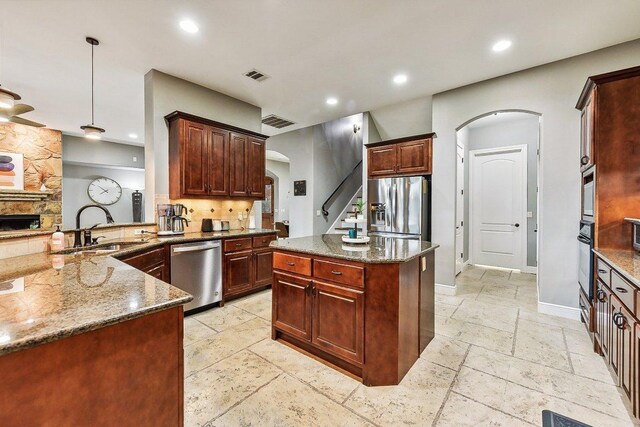 22000 Briarcliff Dr, Spicewood, TX 78669 - kitchen with appliances with stainless steel finishes, arched walkways, stone tile flooring, recessed lighting, and dark stone countertops