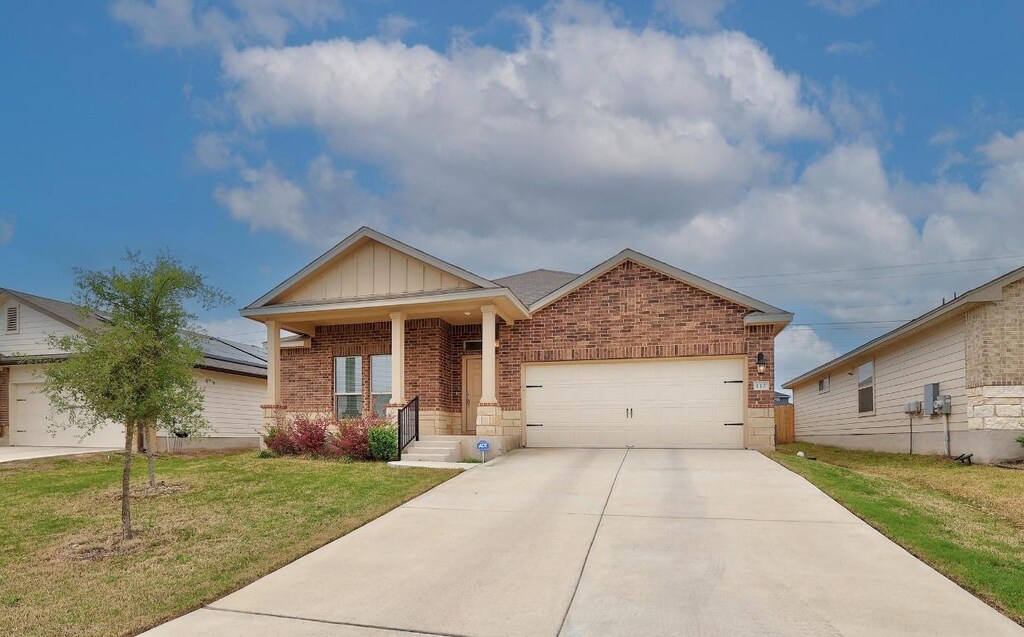 112 Taggart Trl, Jarrell, TX 76537 - view of front facade featuring a garage, concrete driveway, a front yard, brick siding, and board and batten siding