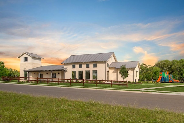 view of front of home featuring a front lawn, metal roof, and playground community