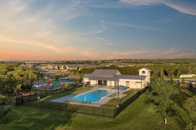 pool at dusk featuring a lawn, a fenced backyard, a community pool, and a patio area