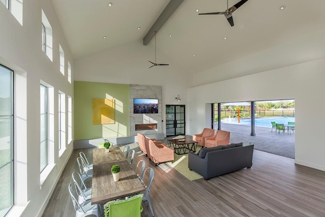 living room featuring a ceiling fan, high vaulted ceiling, beam ceiling, and wood finished floors