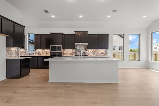 1800 Sauterne Dr, Leander, TX 78641 - kitchen featuring stainless steel microwave, light wood-style flooring, light countertops, black oven, and recessed lighting