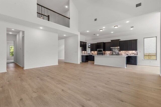 1800 Sauterne Dr, Leander, TX 78641 - unfurnished living room featuring light wood-style floors, a high ceiling, and recessed lighting