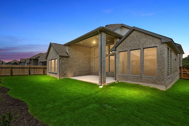 1800 Sauterne Dr, Leander, TX 78641 - back of property at dusk featuring a patio area, a fenced backyard, and brick siding