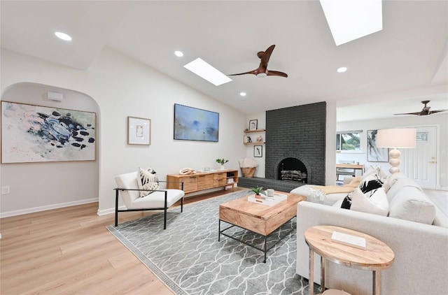 2607 Coatbridge Dr, Austin, TX 78745 - living room featuring a skylight, light wood finished floors, a ceiling fan, vaulted ceiling, and a fireplace