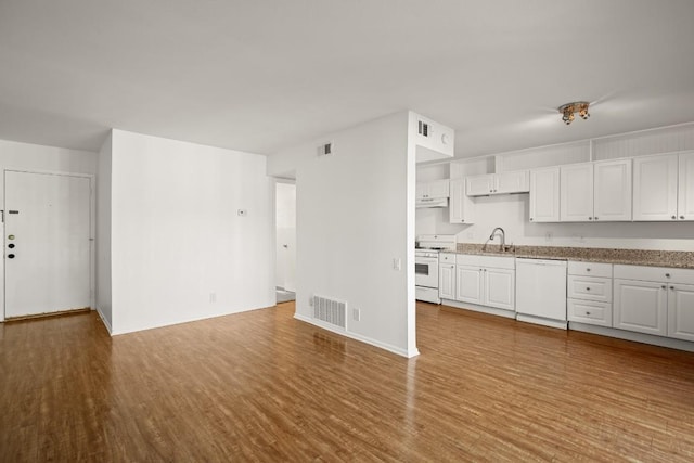 620 S 1st St Unit 209, Austin, TX 78704 - kitchen featuring white appliances, wood finished floors, white cabinets, under cabinet range hood, and light stone counters
