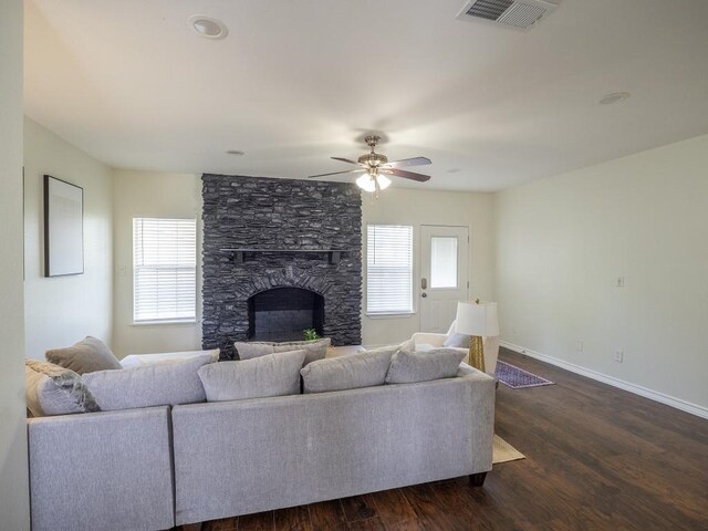 living area featuring dark wood-type flooring, a fireplace, visible vents, and plenty of natural light