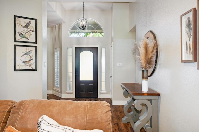 foyer entrance with an inviting chandelier, baseboards, and wood finished floors