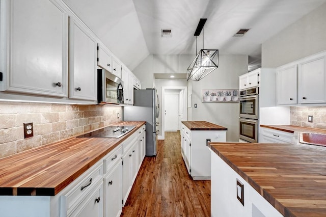 kitchen featuring a center island, visible vents, butcher block counters, and appliances with stainless steel finishes