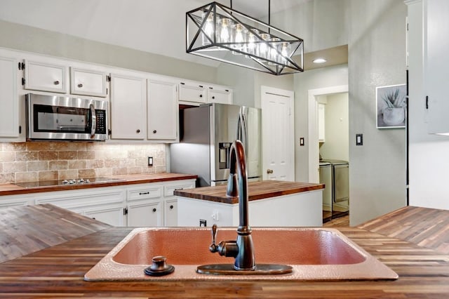 kitchen with backsplash, white cabinets, washing machine and clothes dryer, stainless steel appliances, and wood counters