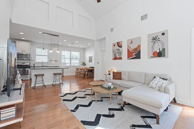 5911 Rubicon Run, Austin, TX 78745 - living area featuring light wood-style flooring, a high ceiling, baseboards, and recessed lighting