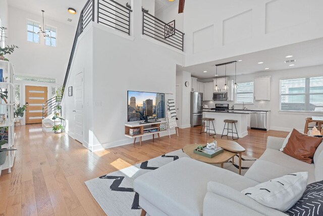 5911 Rubicon Run, Austin, TX 78745 - living room featuring a high ceiling, healthy amount of natural light, baseboards, and light wood-style floors