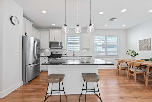5911 Rubicon Run, Austin, TX 78745 - kitchen with stainless steel appliances, a sink, dark countertops, a breakfast bar area, and a center island