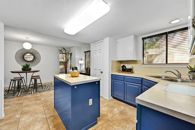 13109 New Boston Bnd, Austin, TX 78729 - kitchen featuring blue cabinetry, a center island, light countertops, a textured ceiling, and white cabinetry