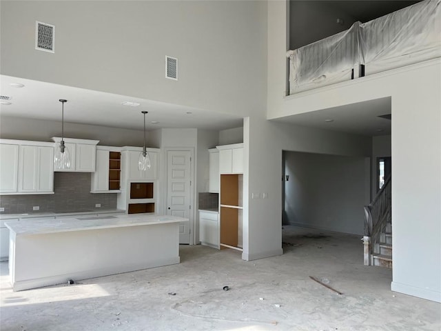 909 Landing Ln, Leander, TX 78641 - kitchen featuring a high ceiling, a center island, backsplash, white cabinetry, and decorative light fixtures