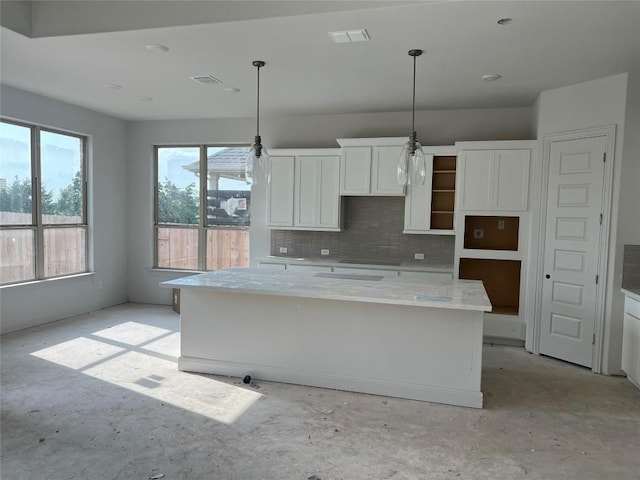 909 Landing Ln, Leander, TX 78641 - kitchen featuring white cabinetry, a center island, decorative backsplash, hanging light fixtures, and unfinished concrete flooring