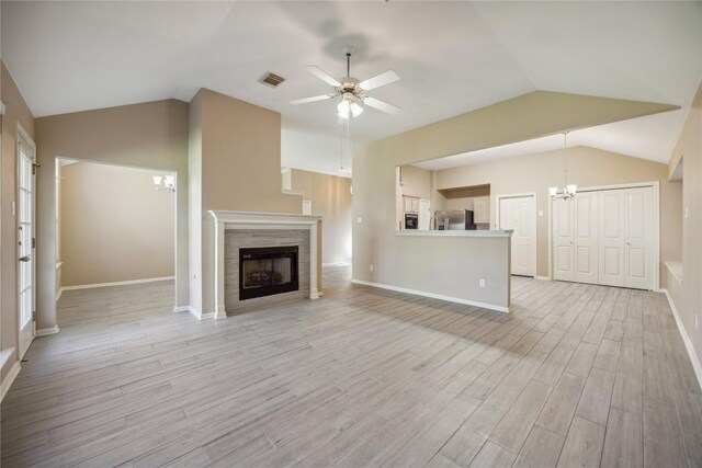 9120 Fainwood Ln, Austin, TX 78749 - unfurnished living room featuring a chandelier, lofted ceiling, light wood-style flooring, a ceiling fan, and a tile fireplace