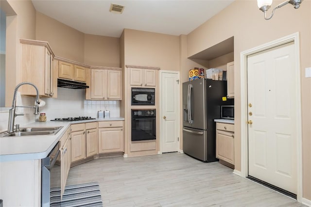 9120 Fainwood Ln, Austin, TX 78749 - kitchen with black appliances, light brown cabinetry, light countertops, decorative backsplash, and light wood-style floors